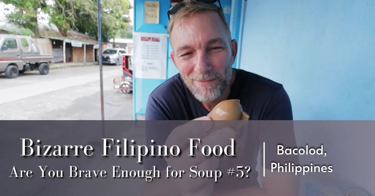Geoff holding a bull testicle from Soup #5 at Siosam’s Food House in Bacolod, Philippines, with a playful smile.