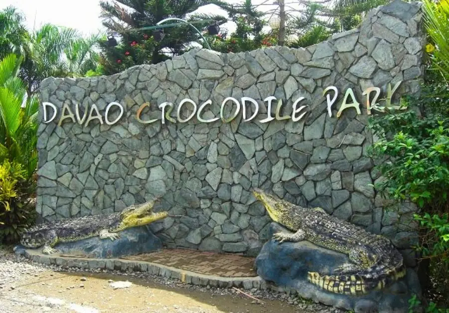 Entrance sign at Davao Crocodile Park with stone wall and crocodile sculptures