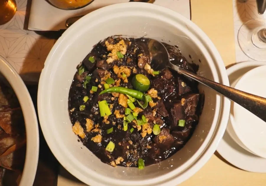 Bowl of dinuguan with green chili, chicharron, and spring onions at Rekado Filipino restaurant in Davao