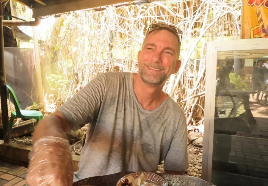 Author smiling at Davao Crocodile Park while eating lechon buwaya