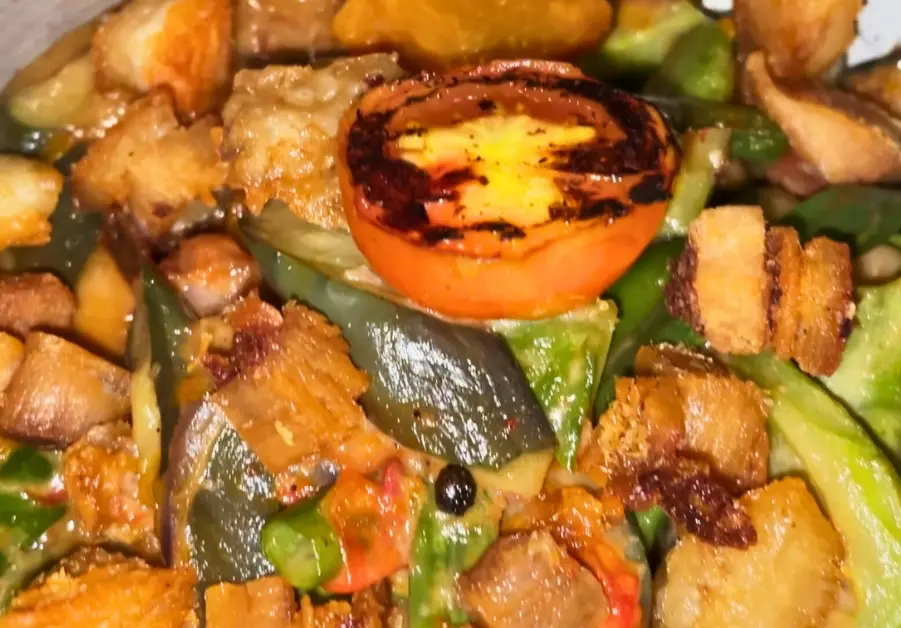Close-up of Rekado’s pinakbet with lechon kawali, vegetables, and grilled tomato