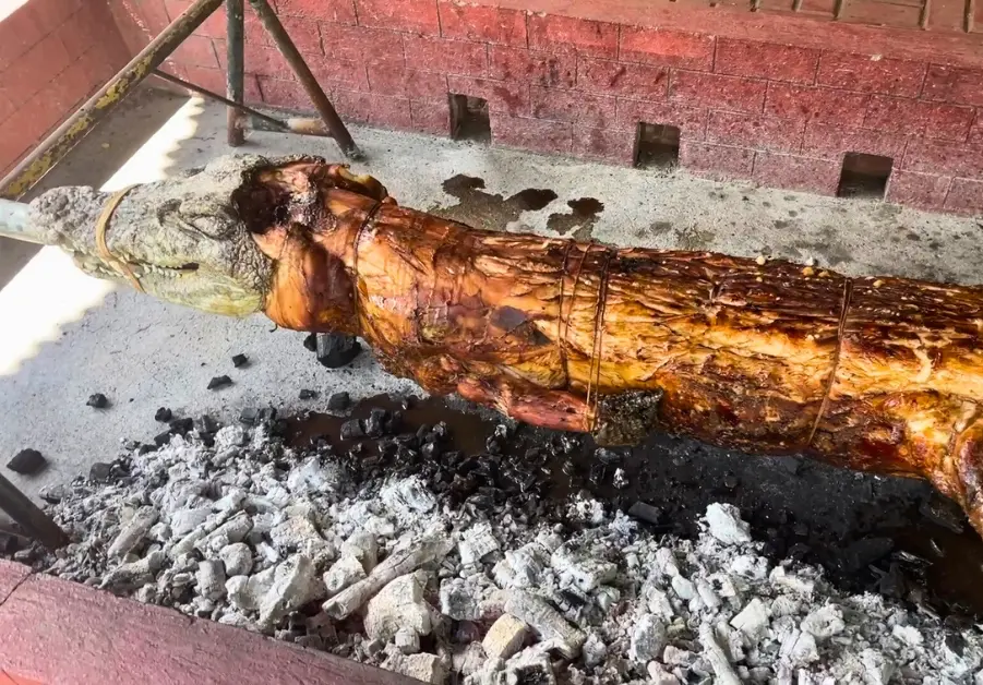 Lechon buwaya roasting whole over charcoal pit at Davao Crocodile Park