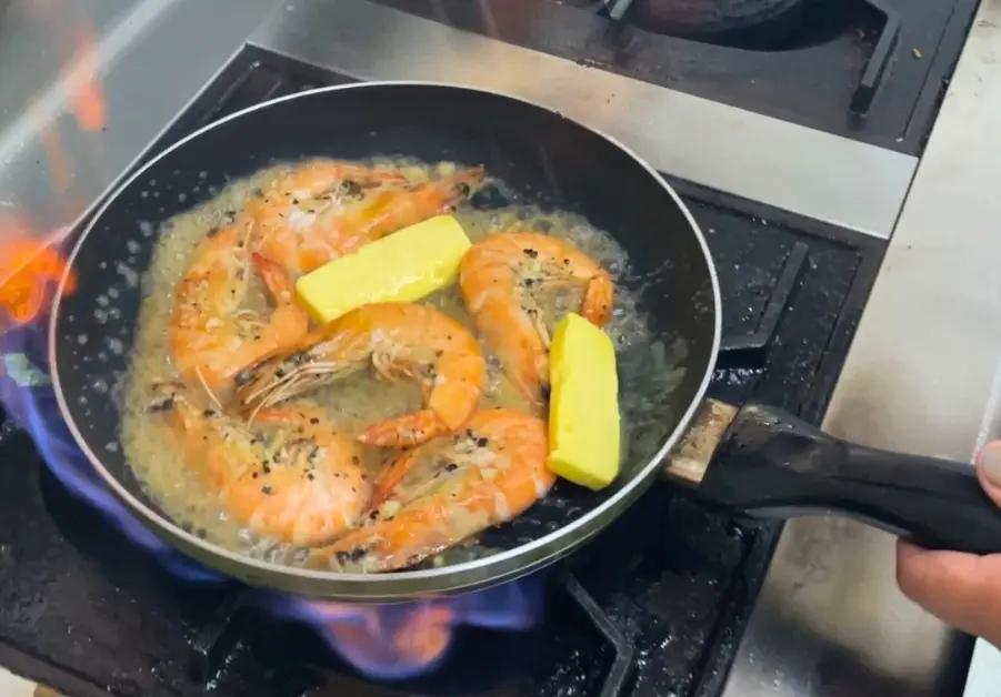 Shrimp cooking in butter and garlic in a pan at Gubat QC kitchen

