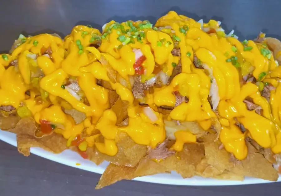 Livestock QC nachos topped with pork adobo, mango salsa, and processed cheese