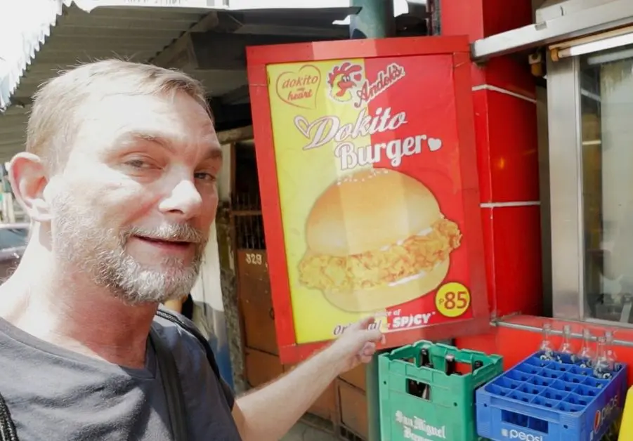 Cheap Eats in Quezon City: Affordable Restaurants and Meals Geoff pointing at the Dokito Burger sign outside an Andok’s branch in Quezon City