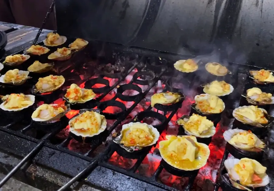 Scallops grilling over a custom circular grate designed for high-volume street cooking.

