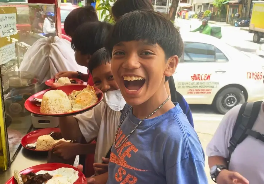 Filipino Street Food: Random Streets in Bago Bantay Filipino school children holding plates of tapsilog at a street food stall in Quezon City