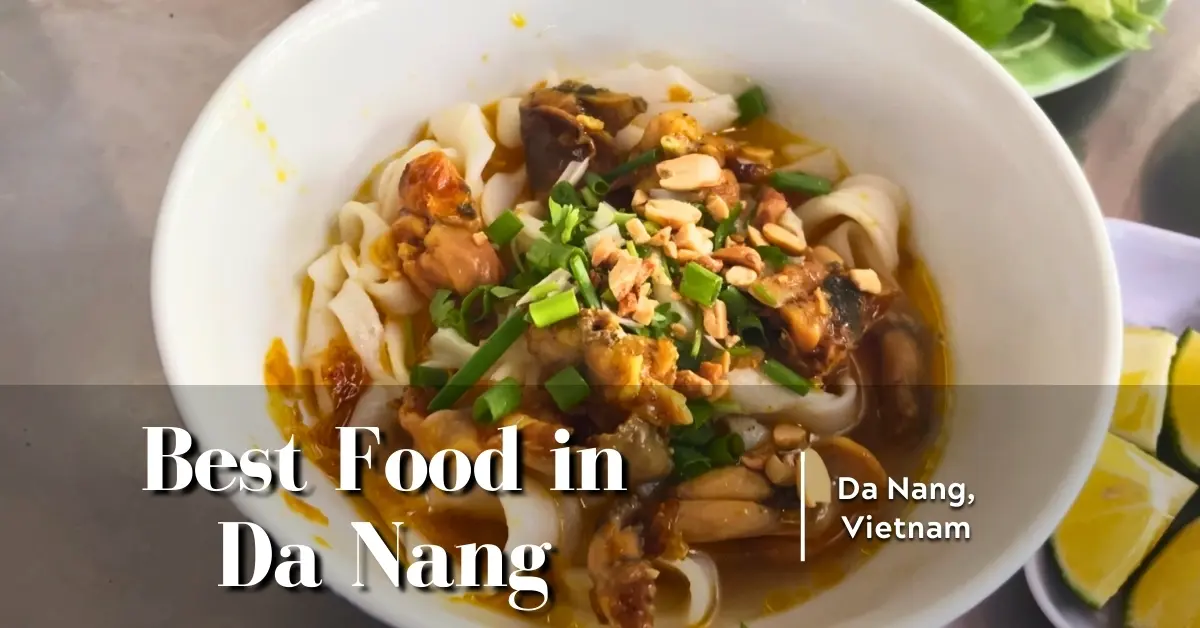 Bowl of mi quang noodles with frog, peanuts, and fresh herbs in Da Nang