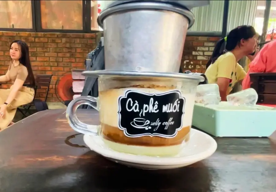 Glass of cà phê muối salted coffee brewing at a cafe in Hue
