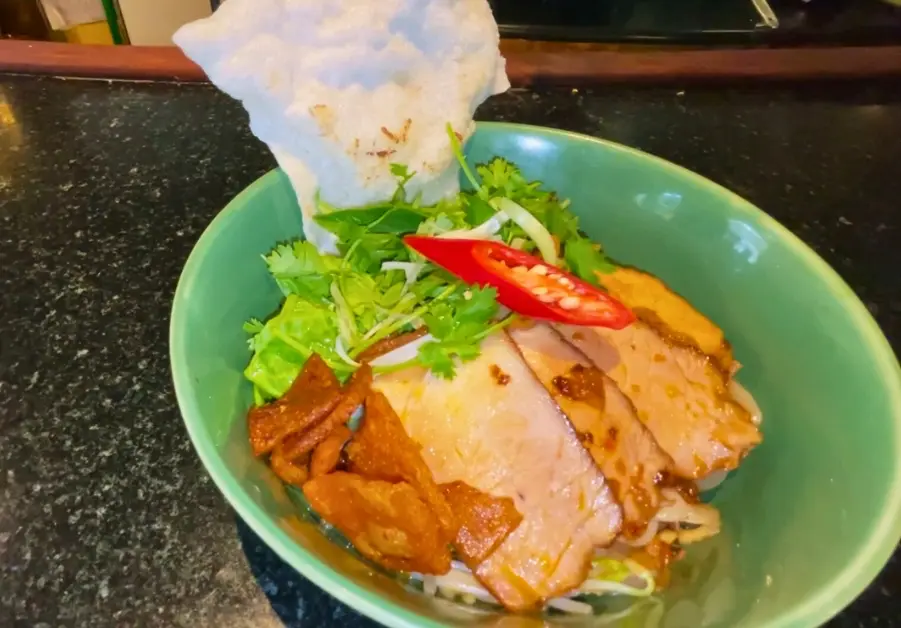 Where to Eat in Hoi An Old Town: 9 Iconic locations Bowl of cao lầu noodles with pork, herbs, and rice cracker at Morning Glory restaurant.