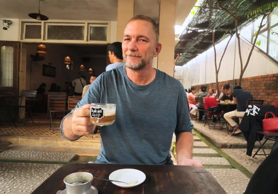 Geoff drinking cà phê muối at the original cafe, showing where to eat in Hue for coffee