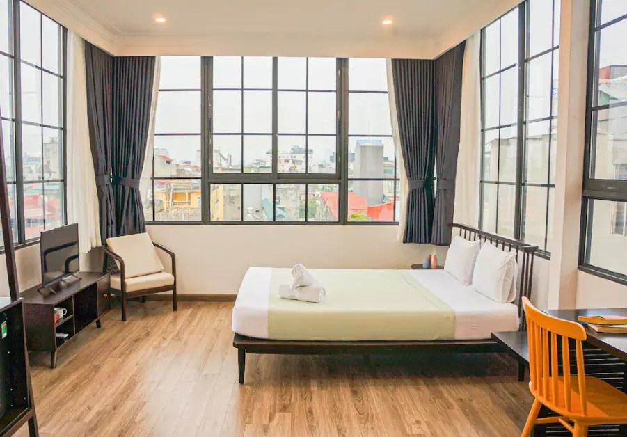 Bright guest room in We Cozy Noi Mieu Hotel Hanoi with large windows and modern furnishings.