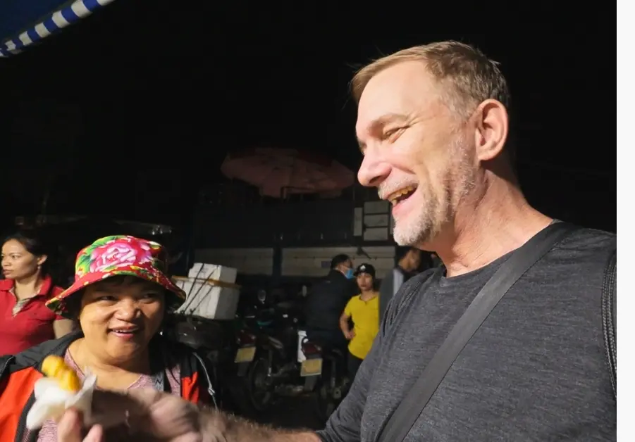 Geoff and Chef Duyên share fried snacks together at Long Biên Market during the early morning tour