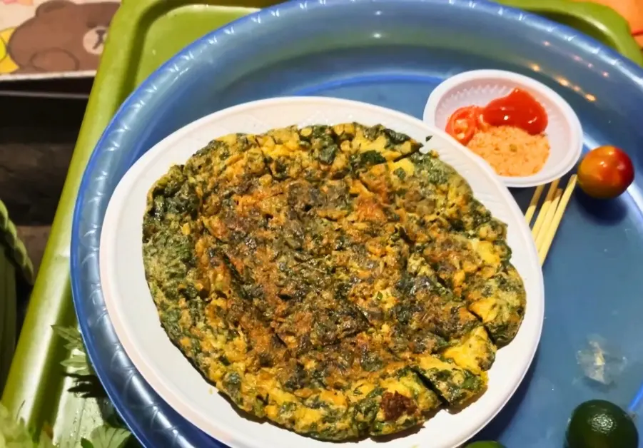 Wild cosmos omelette served on a plate with chili and kumquat dipping salt at Long Biên Market