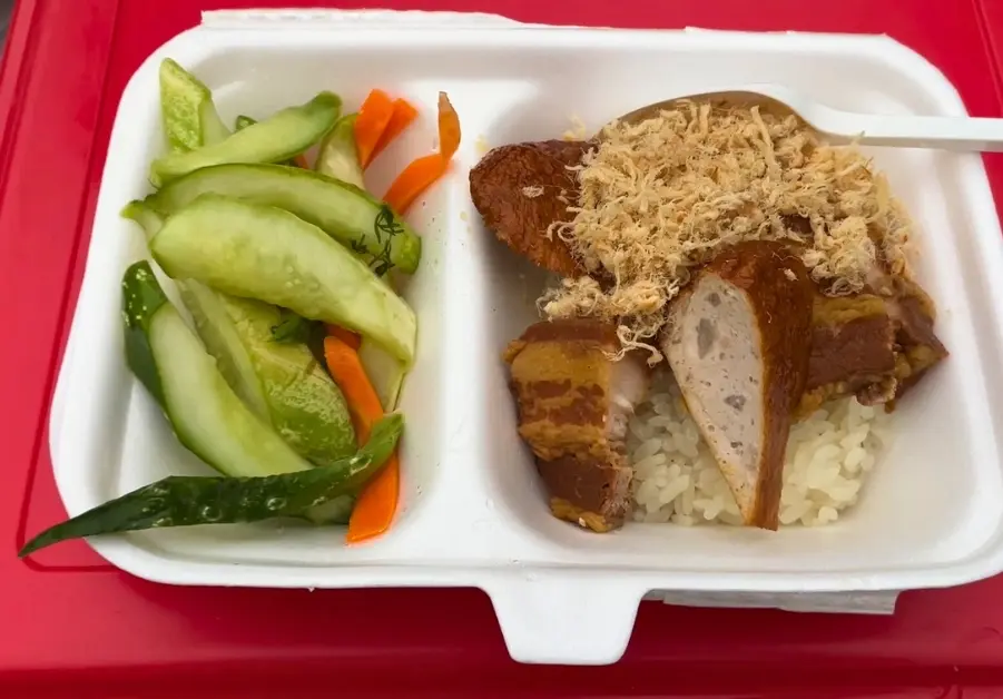 Sticky rice topped with braised pork belly, sausage, and shredded pork floss beside pickled vegetables at Long Bien Market in Hanoi